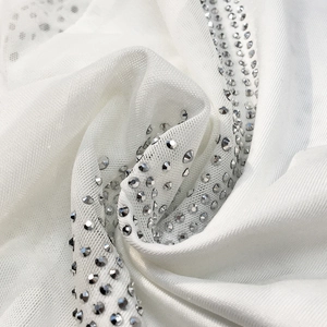 Close-up of white mesh fabric with shimmering silver rhinestones for sexy evening dress