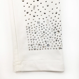 Detail of white knit fabric with sparkling silver rhinestones in geometric shapes