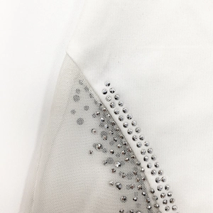 Detailed view of silver rhinestones and mesh stitching on this white evening dress