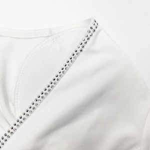 Detailed macro view of white fabric neckline with elegant criss-cross silver rhinestones