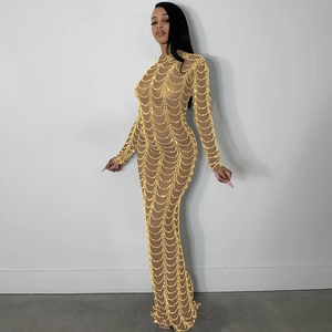 Detail of sheer mesh dress with shimmering golden sequins in wavy patterns