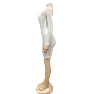 Détail d'une robe en mesh blanc avec strass argentés et manches longues sur modèle