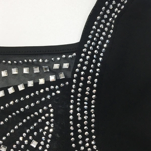 Close-up of sparkling rhinestones in geometric patterns on black mesh fabric sleeve