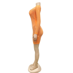 Détail du tissu en maille orange vif avec de petits strass sur une robe courte serrée