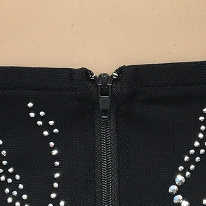 Detail van zwarte mesh jurk met onzichtbare rits en zilveren strass-steentjes in V-patroon
