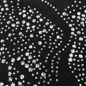 Detailopname van zwarte mesh-stof met verfijnde zilveren strass-steentjes op de jurk