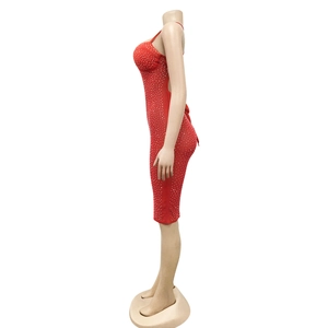 Detail of red bodycon dress featuring thin straps and shimmering rhinestone embellishments