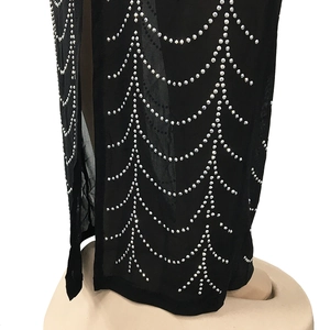 Detailed close-up of sparkling silver rhinestones in a wave pattern on black mesh fabric
