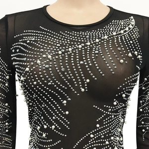 Detail of sheer mesh fabric with intricate pearl and rhinestone wavy patterns