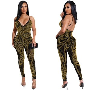 Detail of black mesh jumpsuit with gold rhinestones featuring deep V-neck and open back design
