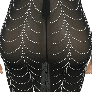 Detail of sheer black mesh dress featuring layered silver rhinestone wave patterns