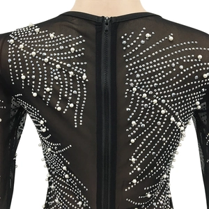Close-up of black mesh dress featuring intricate rhinestone and pearl starburst patterns