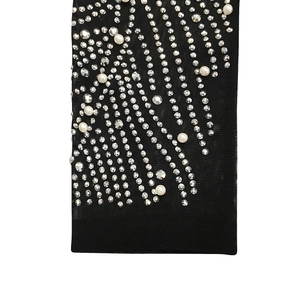 Detailed macro view of sparkling rhinestones and white pearls on black mesh dress fabric