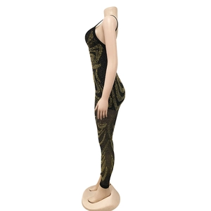 Detail of mesh jumpsuit showing intricate gold rhinestone scroll patterns and sheer fabric