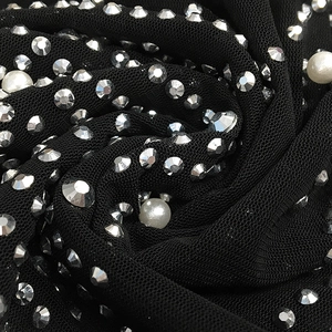 Macro detail of black mesh fabric with silver rhinestones and white pearls on evening dress