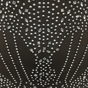 Macro shot of silver rhinestones and geometric crystals on black mesh dress fabric