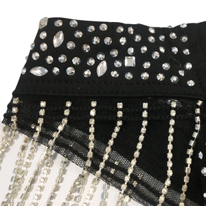 Macro detail of luxury crystal fringe and rhinestones on black mesh party dress