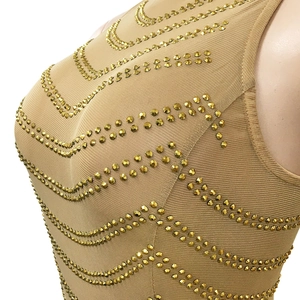 Detail of skin-tone mesh dress with sparkling gold rivets in a wave pattern