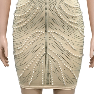 Detail of beige bodycon mini dress featuring intricate V-shaped pearl and rhinestone patterns
