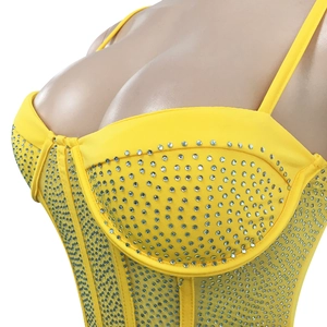 Close-up detail of silver rhinestones on a yellow mesh bustier with spaghetti straps