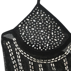 Détail de la robe en maille noire avec des motifs de strass argentés sur l'encolure