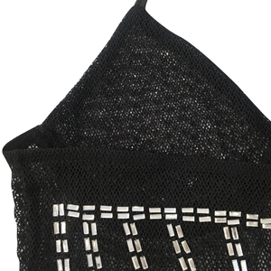 Détail de la robe en maille noire avec strass argentés brillants et décolleté licou