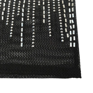 Détail du tissu en maille noire avec des strass ronds et baguettes alignés verticalement