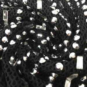 Vue détaillée de strass argentés haute densité sur un tissu de robe en maille noire