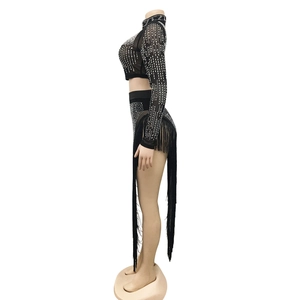 Detail view of black mesh crop top with silver rhinestones and long fringe on shorts