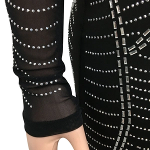 Detail of sheer black mesh sleeves featuring intricate rhinestone wave and stripe patterns