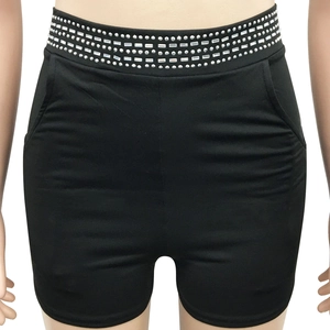 Detail of black high-waisted shorts featuring four rows of silver rivet embellishments