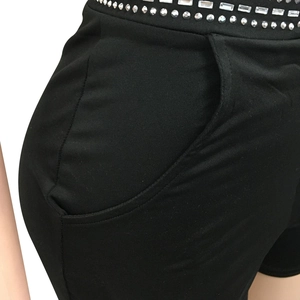 Detailed view of black slim shorts with silver rhinestones and square studs on waist