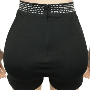 Detail of high-waist black shorts with four rows of silver rhinestones and back zipper