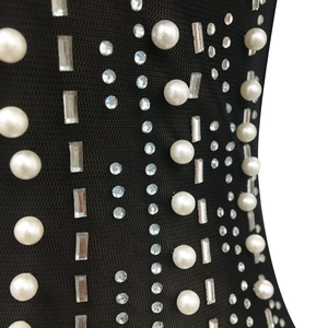 Detailed view of black mesh fabric with intricate pearl and rhinestone embellishments