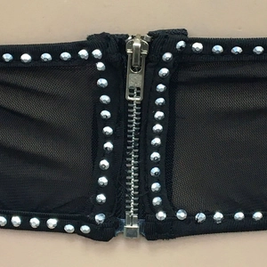 Detail of black mesh corset top with silver rhinestones and central metal zipper