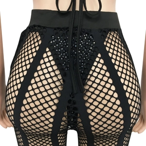 Detail of high-waisted black mesh trousers with sparkling rhinestones and lace-up back