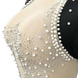 Close-up of white pearls and sparkling rhinestones on sheer nude mesh dress fabric