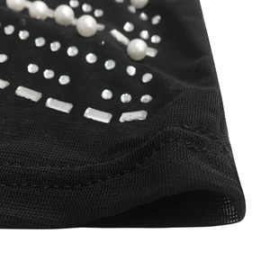 Close-up of mesh fabric with decorative pearls and silver rhinestones on evening dress