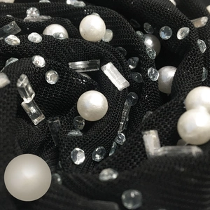 Macro detail of sexy mesh dress fabric with scattered white pearls and sparkling rhinestones