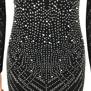 Détail de perles lourdes et strass sur la robe en maille noire transparente