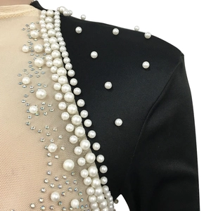Detail of sheer mesh shoulder with faux pearls and rhinestones on black dress