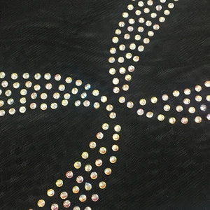 Détail du tissu en maille noire avec strass irisés en motif croisé décoratif