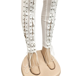 Detail of white trousers featuring full-length metal eyelets and cross-lace design
