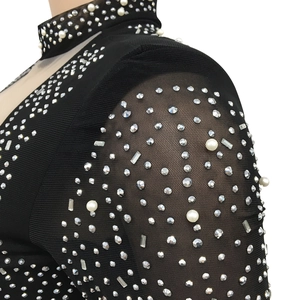 Détail du tissu en maille noire avec strass scintillants et perles blanches sur la robe