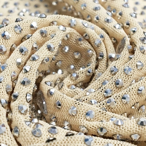 Macro detail of nude mesh fabric with intricate silver rhinestone spiral embroidery