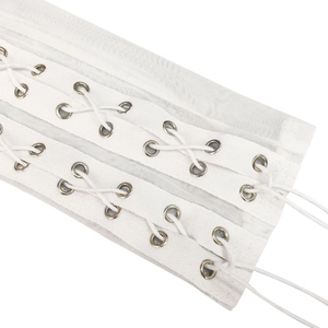 Close-up of white corset belt featuring silver metal eyelets and criss-cross lacing detail