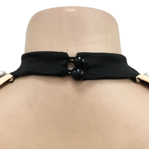 Detail of black halter neckline featuring twin ball buttons and white pearl accents