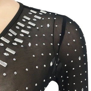 Detailed close-up of sparkling silver rhinestones on sheer black mesh fabric shoulder