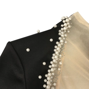 Detailed view of rhinestone and pearl embellishments on sheer mesh sleeve seam