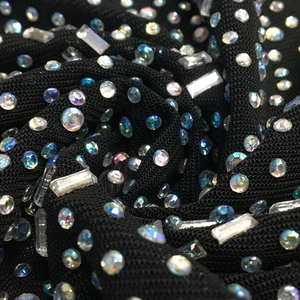 Macro shot of shimmering AB rhinestones on black mesh fabric for a sexy party dress